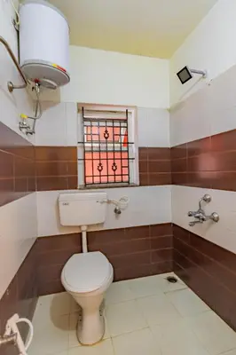 a bathroom with a toilet and a window at A Ooty Garden Residency in Ooty