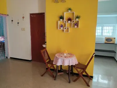 a table and chairs in a room with a yellow wall at A Cozy Homestay in Coimbatore in Coimbatore