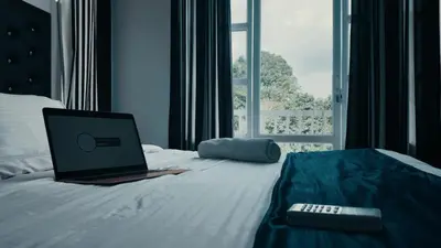 a laptop computer sitting on a bed with a remote control at Aura 2Bedroom Duplex Villa with infinity pool in Kalpetta