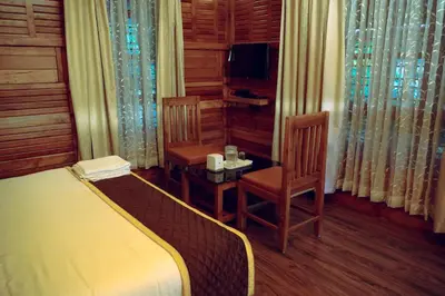 a bedroom with a bed and two chairs and a television at Wood Clusters in Suntikoppa