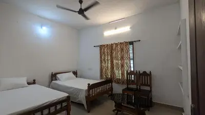 a bedroom with two twin beds and a window at Lush Lagoon Homestay in Ambalavayal