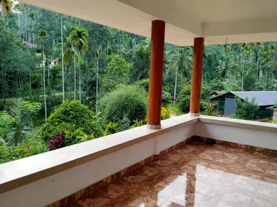 a balcony with a view of the forest at Lush Lagoon Homestay in Ambalavayal