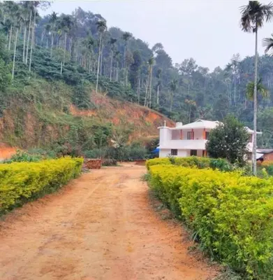 a dirt road in front of a house on a hill at Lush Lagoon Homestay in Ambalavayal