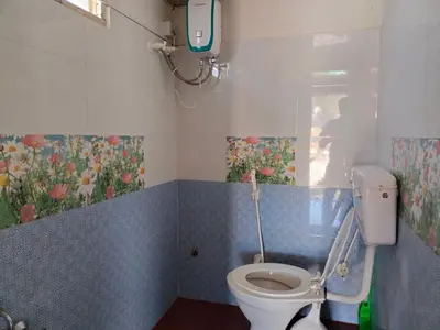 a bathroom with a toilet with a painting on the wall at Laali Penthouse in Madikeri