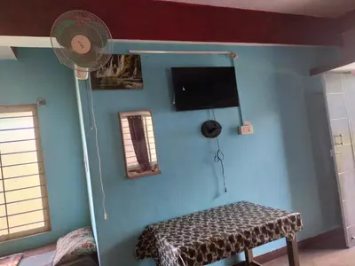 a room with a blue wall with a fan at Laali Dormitory in Madikeri