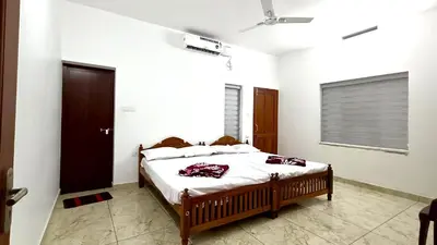 a bedroom with a bed in a white room at Pavans Rainy Days Home Stay in Athirappilly