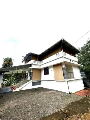 a white house with a black roof at Pavans Rainy Days Home Stay in Athirappilly