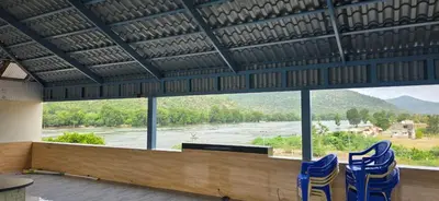 a room with chairs and a view of a river at CS RESORT River point in Wodapatti