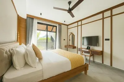 a bedroom with a large bed and a television at Manjoora Saddles Resorts & Spa in Padinjarathara