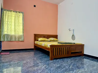 a bedroom with a bed and a yellow curtain at Athithi AC Studio Flat By Shivalaya Stays in Podanūr