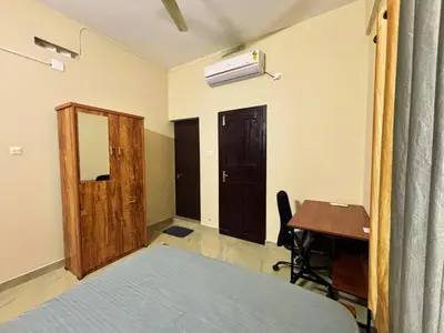 a bedroom with a bed and a desk and a table at Saraa Homes Fully Furnished 2BHK Apartment in Kulattūr