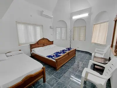 a bedroom with two beds and a chair in it at Guruvayur Agraharam Homestay in Guruvāyūr