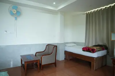 a bedroom with a bed and a chair and a table at Shola Heaven Resort in Kanthalloor