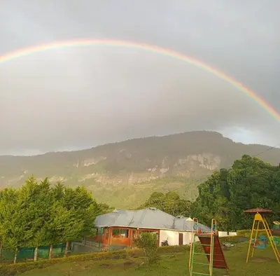 a rainbow over a house with a playground at Shola Heaven Resort in Kanthalloor