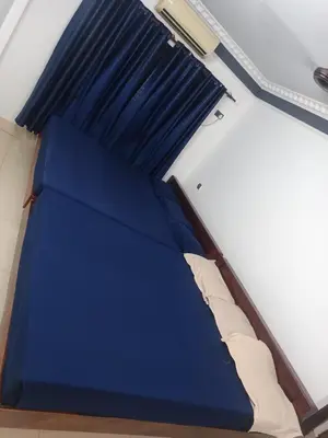 a bed in a room with blue sheets and a pillow at Poonthanam guest house in Guruvāyūr
