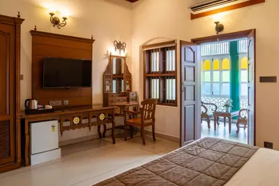 a bedroom with a bed and a desk with a television at Villa de 1945 in Mahe