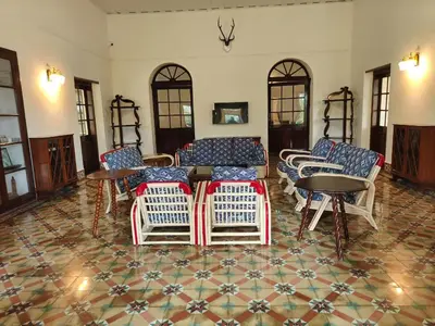 a living room with chairs and a table with books at The Estate Bay by Z Vacations in Gonikoppal