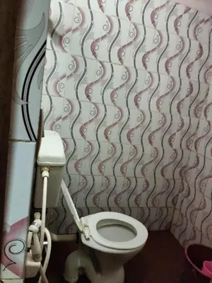 a bathroom with a toilet and a wall at Laharya couple room in Madikeri