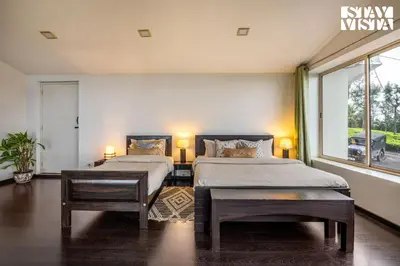 a bedroom with two beds and a window at StayVista at Sande's Farview with Bonfire in Coonoor