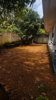 a dirt yard next to a house with a fence at Niel Valley Homestay - Poomala in Mulagunnathukāvu