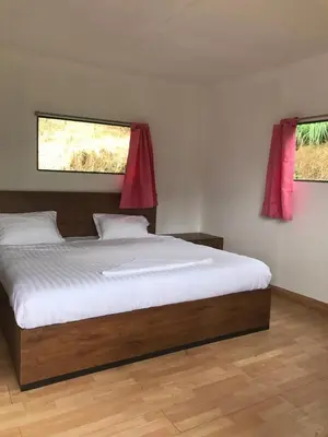 a bedroom with a large bed with two windows at Lone Tree Creek in Vattavada