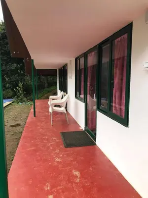 a house with a red floor and a chair on a porch at Lone Tree Creek in Vattavada