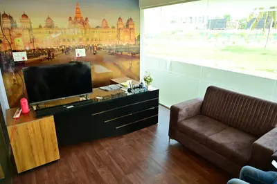 a living room with a flat screen tv and a couch at Oasis Service Apartments in Mysore