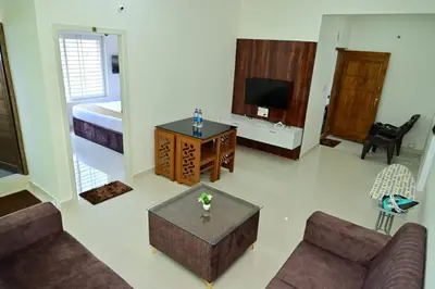 a living room with a couch and a television at Oasis Service Apartments in Mysore