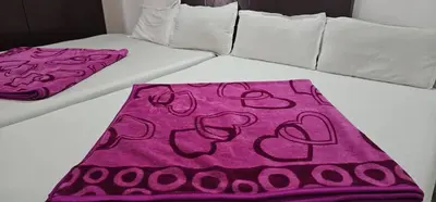 a white bed with a pink blanket on it at The Green Regency Annexe in Munnar