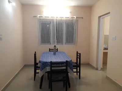 a dining room with a table and chairs and a window at NectorNest in Kodaikānāl