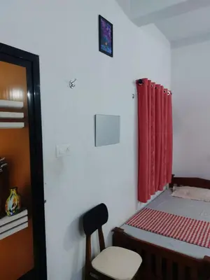 a small room with a bed and a red curtain at Fathima Arcade Lodge