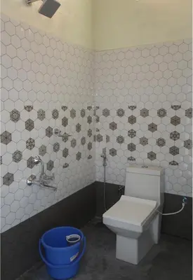 a bathroom with a toilet and a blue bucket at River point homestay in Kushālnagar