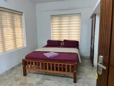 a bedroom with a bed with purple sheets and windows at Dragster Homes Alwaye in Alwaye