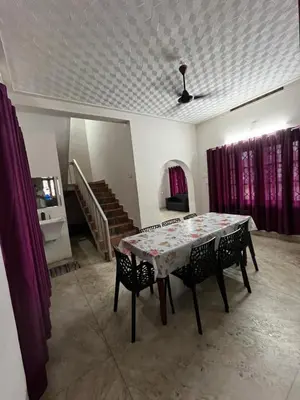 a dining room with a table and chairs with purple curtains at Dragster Homes Alwaye in Alwaye