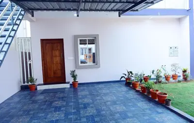 a white house with potted plants and a door at PuMi Residence in Vānivilāsa Puram