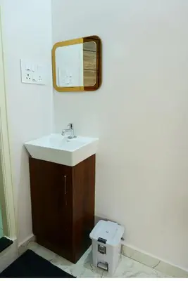 a bathroom with a sink and a mirror and a toilet at PuMi Residence in Vānivilāsa Puram