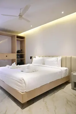 a bedroom with a large white bed with a ceiling at Hotel Shellmark in Elivāla