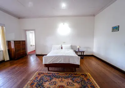 a bedroom with a bed and a rug on a wooden floor at Arivikad Tea Bungalow Munnar By VOYE HOMES in Munnar