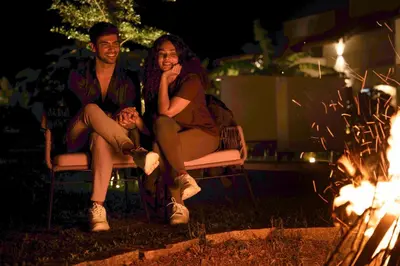 a man and a woman sitting on chairs next to a fire at Wild Origin Kabini - A Luxury Resort in Kabini River