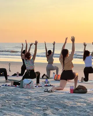 a group of women doing yoga on the beach at Seawind in Kannur