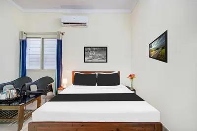 a bedroom with a bed and two chairs at Collection O Mysore Shri Lakshmikantha Swamy Temple in Mysore