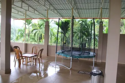 a room with a bed and chairs and palm trees at Safari Inn in Kurchi