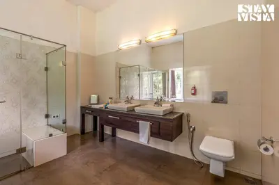 a bathroom with two sinks and a shower and a toilet at StayVista at Farview Presidential Suite with Lawn, Bonfire & Bathtub in Kotagiri