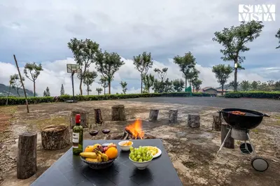 a grill and a table with food and a fire at StayVista at Farview Presidential Suite with Lawn, Bonfire & Bathtub in Kotagiri