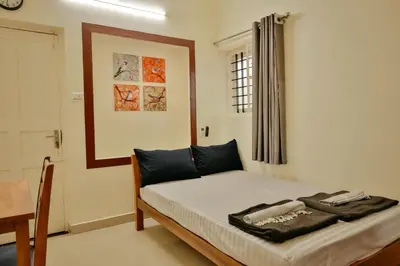 a bedroom with a bed and a table and a window at Nila Heavens - Spacious 5 BHK Homestay , ideal for families in Guruvāyūr