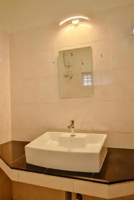 a bathroom with a white sink and a mirror at Nila Heavens - Spacious 5 BHK Homestay , ideal for families in Guruvāyūr