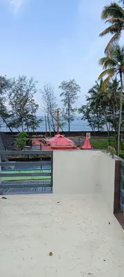 a white wall with a gate and some palm trees at Seascape Homestay Cherai Beach in Cochin