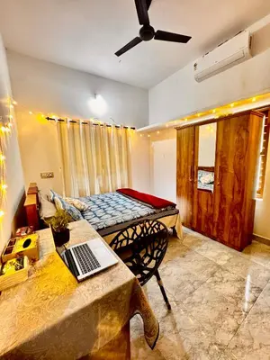 a room with a bed and a table with a laptop on it at Nirvana Stays Banasura, Wayanad in Wayanad