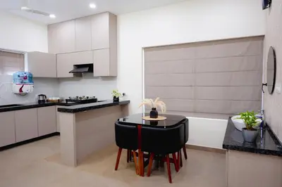a kitchen with white cabinets and a black table and chairs at Zainab in Kozhikode