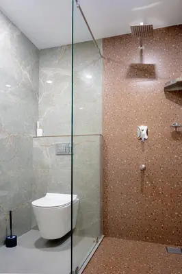 a bathroom with a toilet and a glass shower at Zainab in Kozhikode